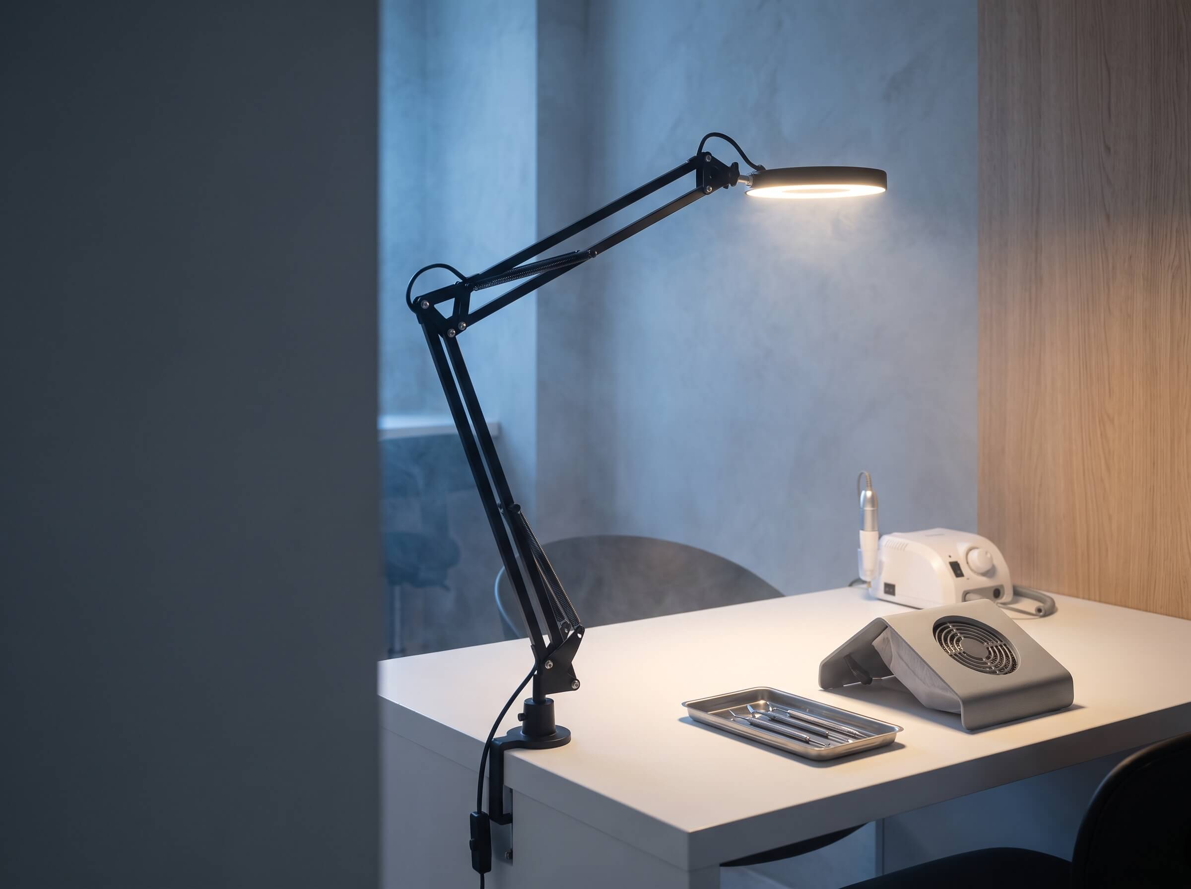 Student workstation with a lit lamp prepared for a basic manicure lesson